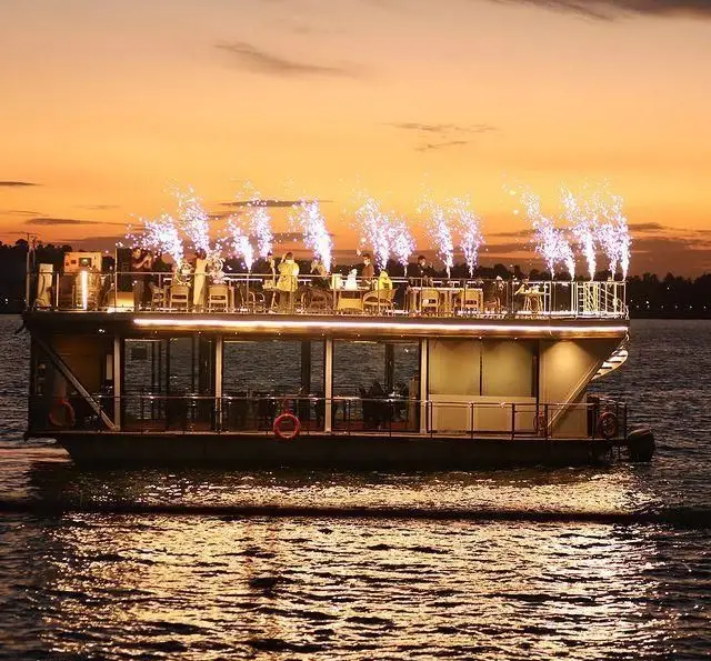 کشتی رستوران رویال لانژ در غروب دل‌انگیز، با نورپردازی و فواره‌های درخشان، فضایی عالی برای مهمانی‌ها و لحظات به یادماندنی.