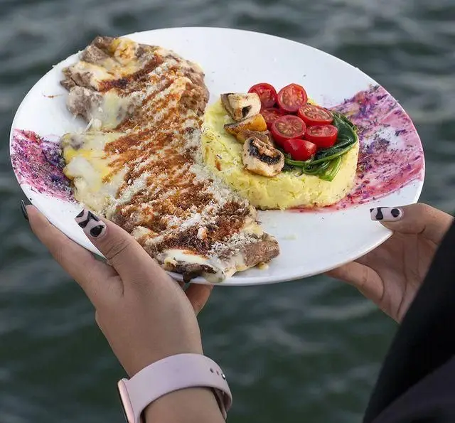 استیک پنیردار لذیذ با پوره سیب‌زمینی، قارچ، گوجه گیلاسی و اسفناج تازه، غذایی خوشمزه در کشتی رستوران رویال لانژ بر روی آب.