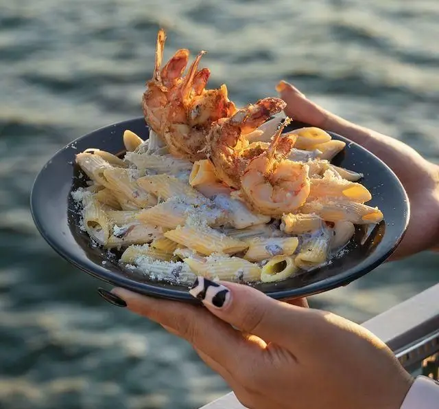 پاستا میگو گریل شده با سس سفید و پنیر، یک غذای اشتهاآور در کشتی رستوران رویال لانژ با پس زمینه دریا و منظره ای رویایی.