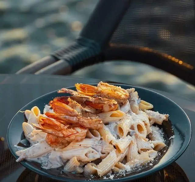 پاستا پنه با سس آلفردو و میگوهای گریل شده رویال لانژ؛ غذایی دریایی و خوشمزه در محیط آرامش‌بخش کشتی رستوران.