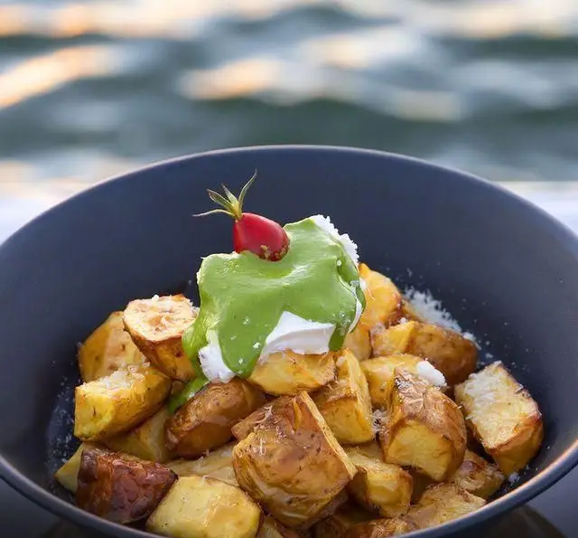 سیب زمینی تنوری لذیذ با سس سبز و خامه، سرو شده در کشتی رستوران رویال لانژ با منظره زیبای دریا. یک غذای خاص و متفاوت.