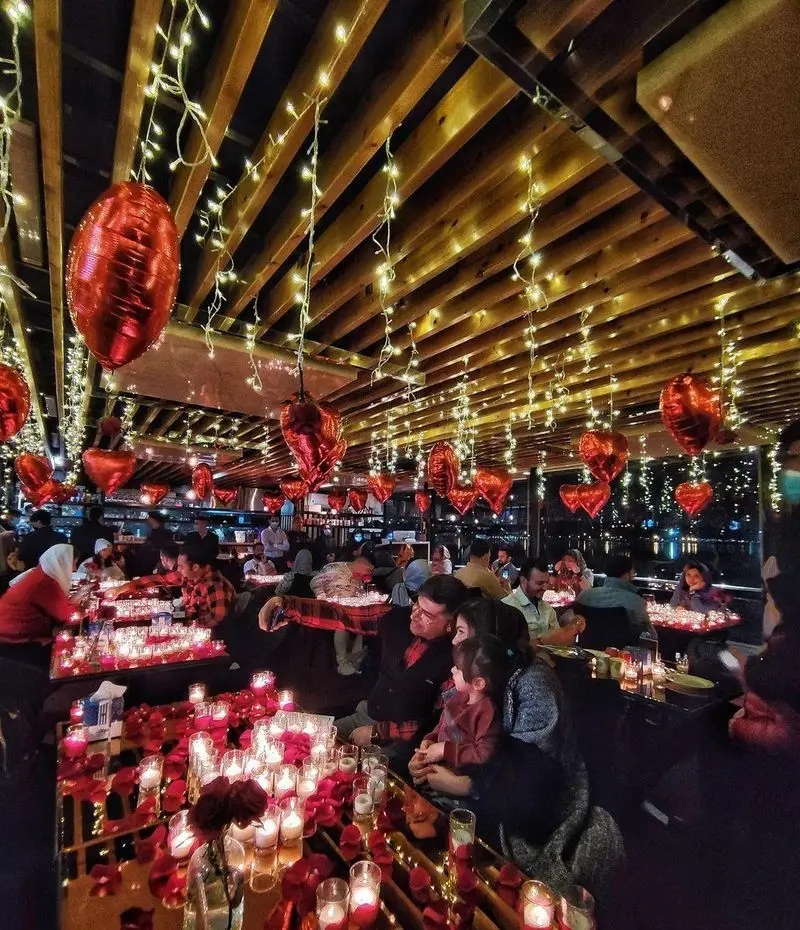 فضای داخلی کشتی رستوران رویال لانژ، با دکوراسیون رمانتیک شامل بادکنک‌های قلبی قرمز، ریسه‌های نورانی و شمع و گلبرگ رز.