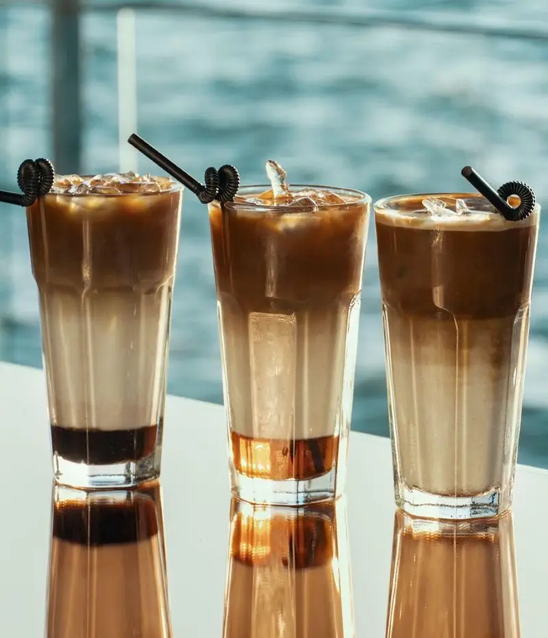 لذت سه لیوان قهوه سرد لایه ای خنک و گوارا با چشم انداز آبی دریا در کشتی رستوران رویال لانژ، انتخابی دلنشین برای آرامش.