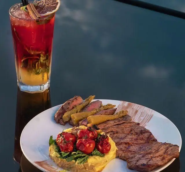 تجربه یک شام لوکس: استیک آبدار گریل شده با گارنیش مارچوبه و گوجه در کنار کوکتل تابستانی در کشتی رستوران رویال لانژ.