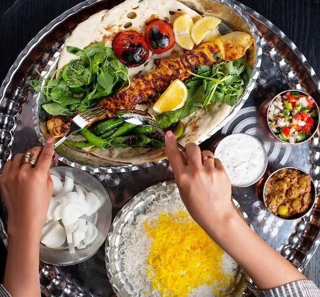 کبابسرای شب زدگان: یک سینی مجلل کباب ایرانی شامل جوجه کباب، گوجه، پیاز، فلفل کبابی، برنج زعفرانی و مخلفات تازه.
