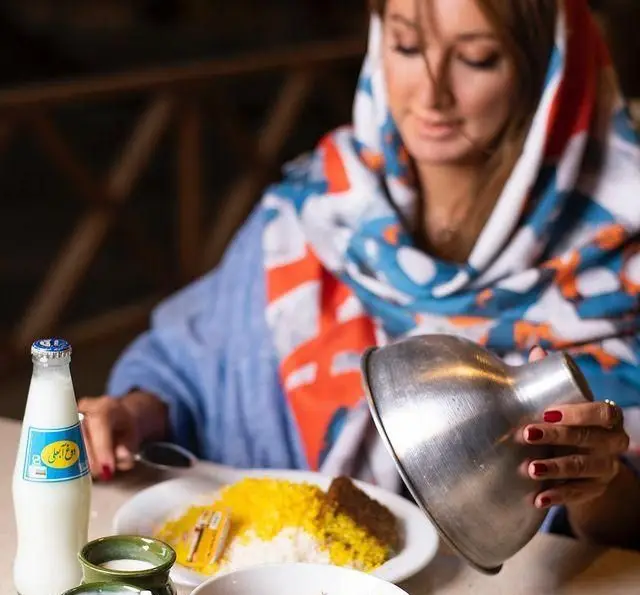 مشتری در کبابسرای شب زدگان، در حال سرو دیزی یا آبگوشت با برنج و دوغ عالی. لذت غذای سنتی ایرانی در فضایی دلنشین.