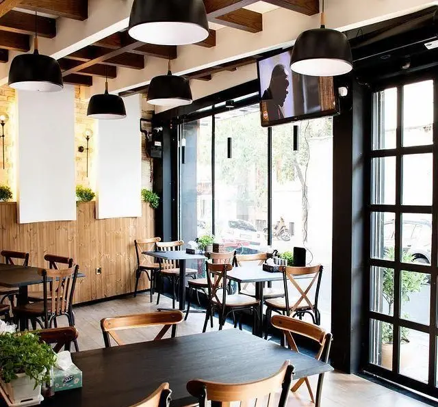 فضای داخلی جذاب و دلنشین کبابسرای شب زدگان، دارای دکوراسیون چوبی، میز و صندلی‌های شیک، نورپردازی مدرن و پنجره‌های بزرگ با نور طبیعی.