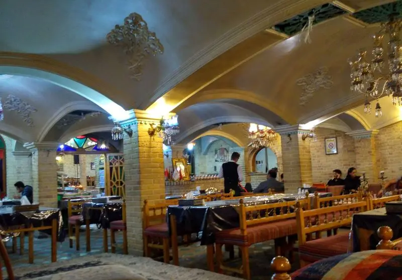 تصویری از سفره خانه سنتی هزار دستان با محیطی گرم و دلپذیر، طاق‌های آجری، لوسترهای قدیمی و چیدمان سنتی برای تجربه ای اصیل.