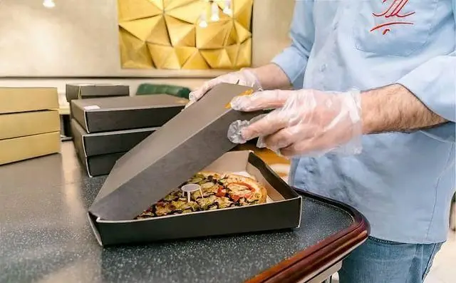 کارکنان رستوران پلاک در حال بسته‌بندی پیتزاهای تازه و باکیفیت، با رعایت کامل بهداشت و استفاده از جعبه‌های مخصوص جهت ارسال و تحویل.