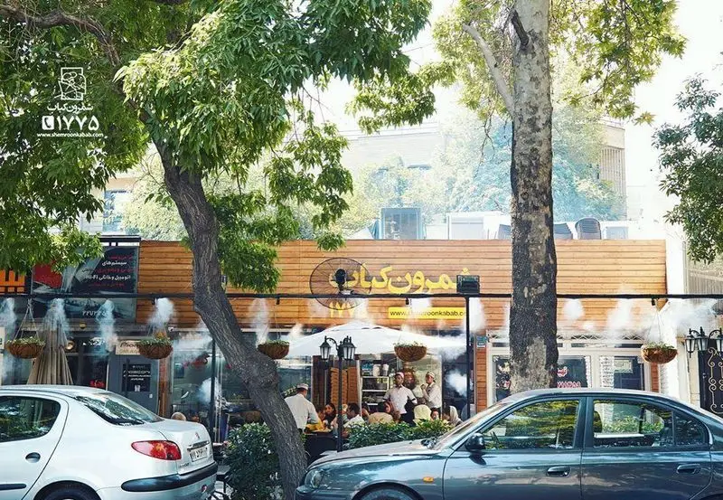 نمای خارجی رستوران شمرون کباب با فضای باز دلنشین، درختان سرسبز و مشتریان در حال لذت بردن از غذا و کباب.