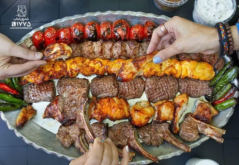 سینی بزرگ کباب شمرون شامل جوجه کباب، کباب کوبیده، شیشلیک و برگ به همراه گوجه و فلفل کبابی. لذت غذای اصیل ایرانی.