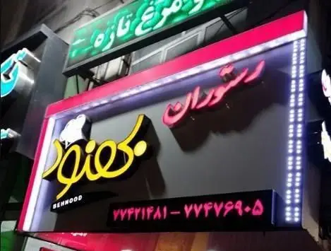 تابلو نئون و زیبای رستوران ایرانی بهنود در شب با لوگوی کلاه سرآشپز و شماره تماس. مکانی عالی برای تجربه غذاهای اصیل ایرانی.