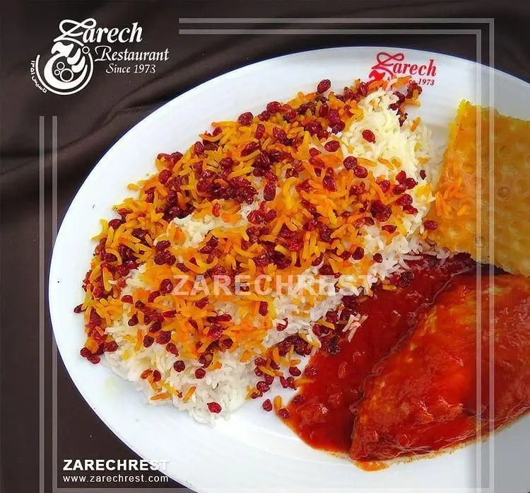 تصویر وسوسه‌انگیز از زرشک پلو با مرغ سنتی، برنج زعفرانی، دانه‌های زرشک و ته دیگ طلایی در رستوران زرچ، تجربه‌ای از طعم اصیل ایرانی.