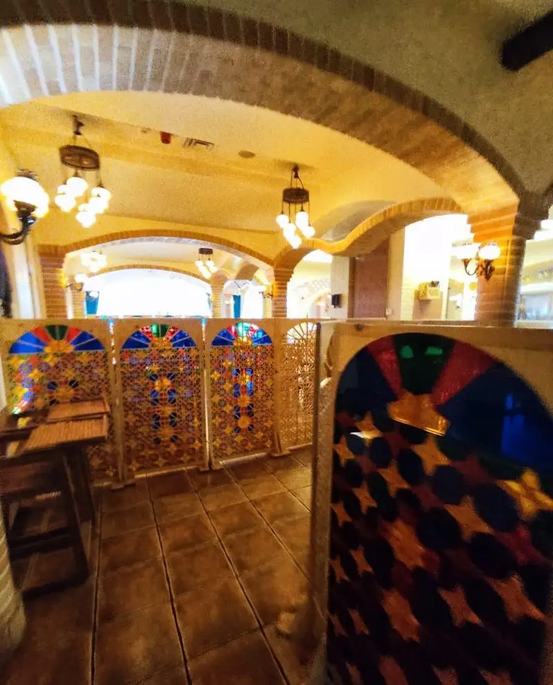 فضای داخلی لوکس و دلنشین رستوران مسینه، با معماری آجری قوسی، لوسترهای آویز و پارتیشن‌های طرح‌دار شیشه‌رنگی زیبا.