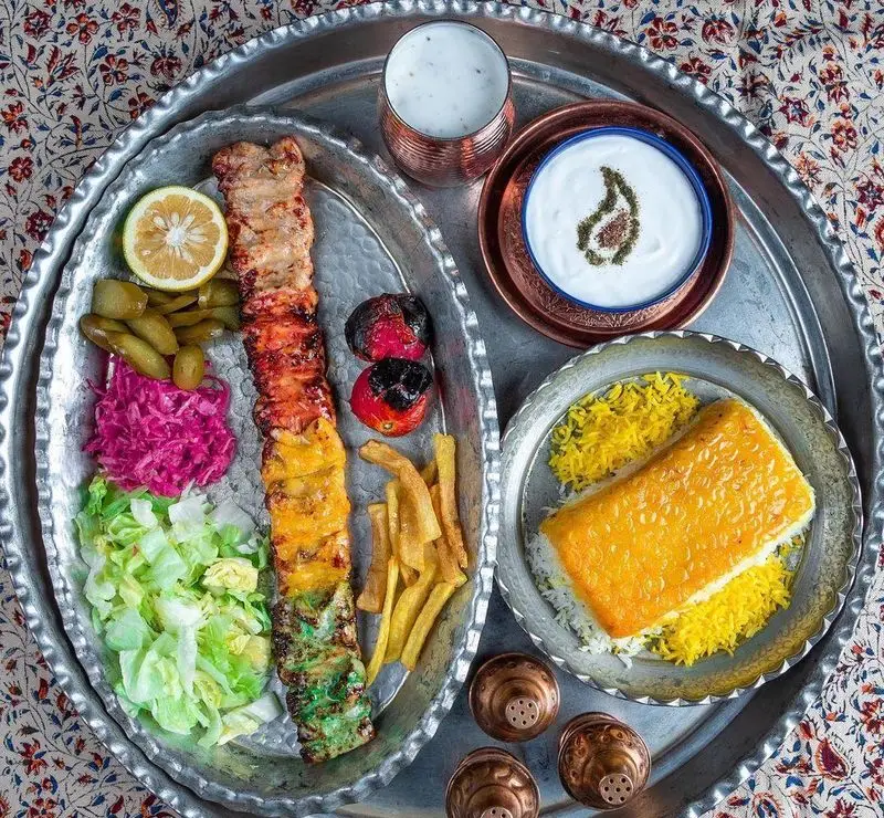 سفره کامل و زیبای رستوران مسینه با کباب‌های رنگی جوجه و کوبیده، ته دیگ زعفرانی، برنج، سالاد، مخلفات و دوغ.