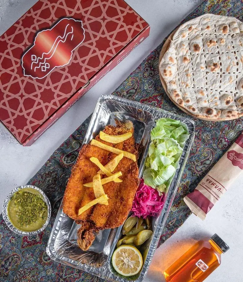 سفارش آنلاین غذای ماهی سوخاری رستوران مسینه در سینی یکبار مصرف، همراه با نان داغ، سالاد و دورچین. مناسب دلیوری غذای ایرانی.