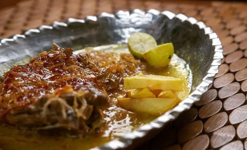غذای سنتی ایرانی رستوران مسینه شامل گوشت لذیذ با سس مخصوص، پیاز داغ، سیب‌زمینی و لیمو در ظرف مسی زیبا