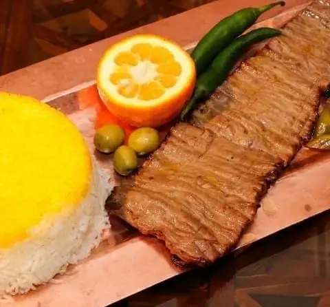 چلوکباب برگ لذیذ با برنج زعفرانی، پرتقال، فلفل و زیتون در کافه رستوران سنتی قصر ایرانیان، نمادی از غذای اصیل ایرانی.