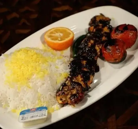 غذای کامل ایرانی: چلو کباب مرغ آبدار با برنج زعفرانی، گوجه کبابی و لیمو، سرو شده در کافه رستوران قصر ایرانیان