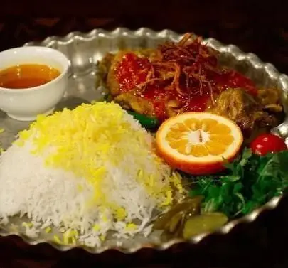 لذت چشیدن چلو مرغ زعفرانی و اصیل کافه رستوران سنتی قصر ایرانیان؛ غذایی خوش‌رنگ و آبدار با تزیین پیازداغ و نارنج تازه.
