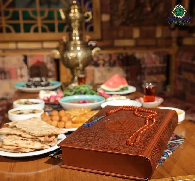 چیدمان زیبای سفره افطار در کافه رستوران سنتی قصر ایرانیان، همراه با غذاهای اصیل ایرانی، شیرینی‌جات، چای و قرآن.