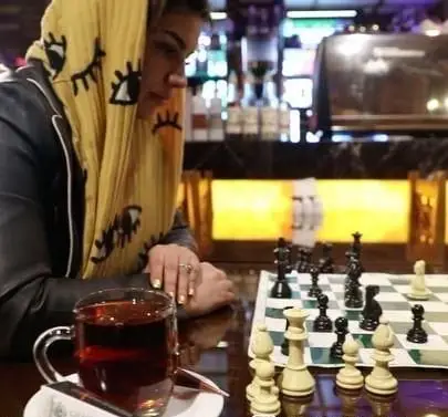 مشتری در کافه رستوران سنتی قصر ایرانیان مشغول بازی شطرنج و نوشیدن چای، نشان دهنده فضای دنج و سرگرمی مجموعه.