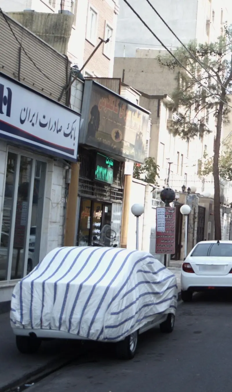 نمایی از خیابان شلوغ شهری در تهران با رستوران کبابسرای کاکتوس و بانک صادرات ایران، به همراه خودروها و ساختمان‌های منطقه.