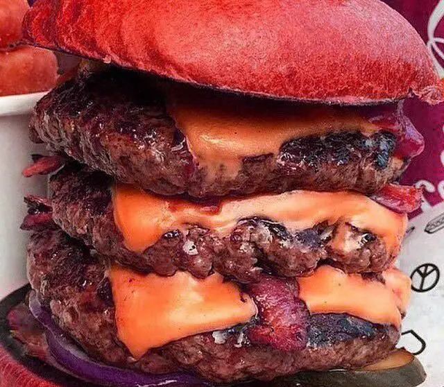 چیزبرگر سه لایه رستوران مازستا با نان قرمز، پتی‌های گوشت آبدار، پنیر ذوب شده، بیکن، پیاز قرمز و خیارشور.