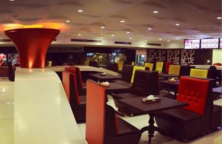 فضای داخلی جذاب و مدرن رستوران مازستا، شامل میز و صندلی‌های شیک قرمز، زرد و قهوه‌ای، همراه با نورپردازی دلنشین و طراحی خاص.
