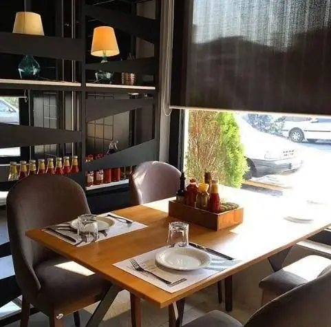 فضای داخلی مدرن فست فود روکو با میز غذاخوری چوبی، صندلی‌های راحت، قفسه‌های دکوراتیو و سس‌های متنوع برای تجربه غذایی دلپذیر.