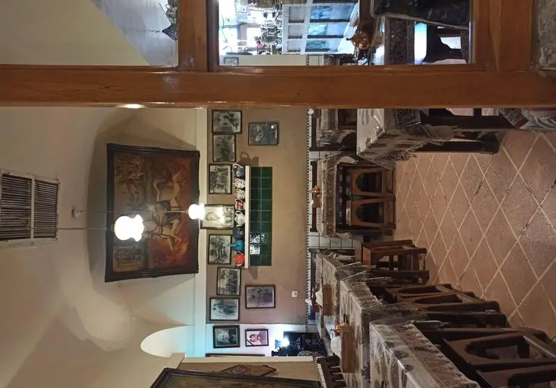 فضای داخلی رستوران ایرانی آذری با میز و صندلی‌های چوبی، کفپوش کاشی‌کاری سنتی، نقاشی‌ها و قاب عکس‌های دیواری، و دکوراسیون دنج.