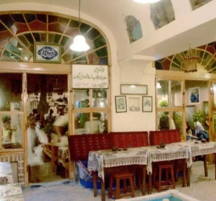 تصویر داخلی رستوران سنتی ایرانی آذری با محیطی دلنشین، دکوراسیون زیبا، میز و صندلی‌های چوبی و پنجره‌های ارسی خیره‌کننده.