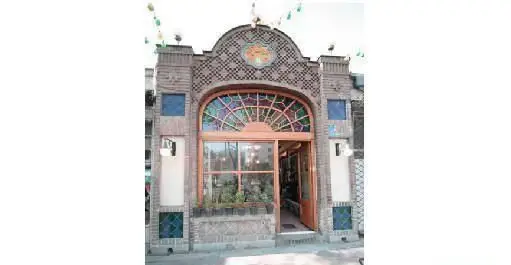 نمای بیرونی رستوران ایرانی آذری با معماری منحصر به فرد، آجرکاری و کاشی‌کاری هنرمندانه، و درب ورودی با شیشه‌های رنگی خیره‌کننده.