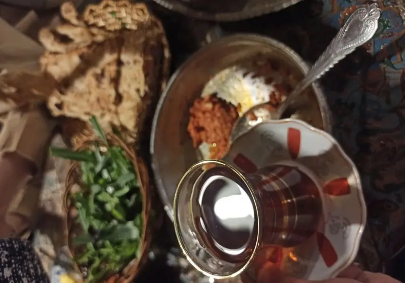 سفره‌ آرایی دلنشین در رستوران ایرانی آذری: نان تازه، سبزی خوردن، غذای اصیل و چای گرم. تجربه‌ای ناب از طعم‌های سنتی.