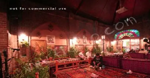 فضای داخلی زیبای رستوران سنتی ایرانی آذری با دکوراسیون گرم، فرش‌های دستباف و پنجره‌های رنگی، محیطی آرام برای تجربه غذاهای لذیذ.