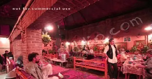 نمایی از فضای داخلی رستوران سنتی ایرانی آذری با معماری آجری، نورپردازی گرم و مشتریانی در حال لذت بردن از غذا.