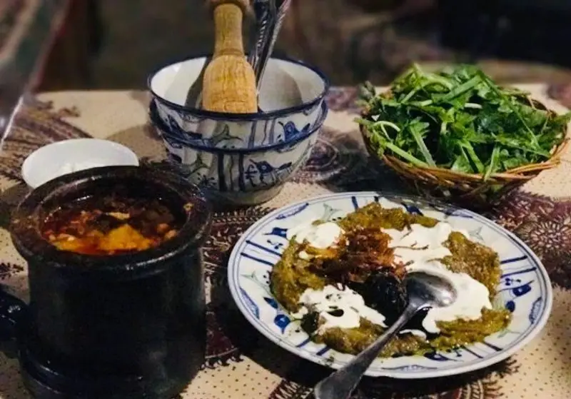 غذای سنتی ایرانی آذری شامل دیزی، کشک بادمجان و سبزی خوردن تازه در رستوران آذری با ظروف سفالی و سرو سنتی.