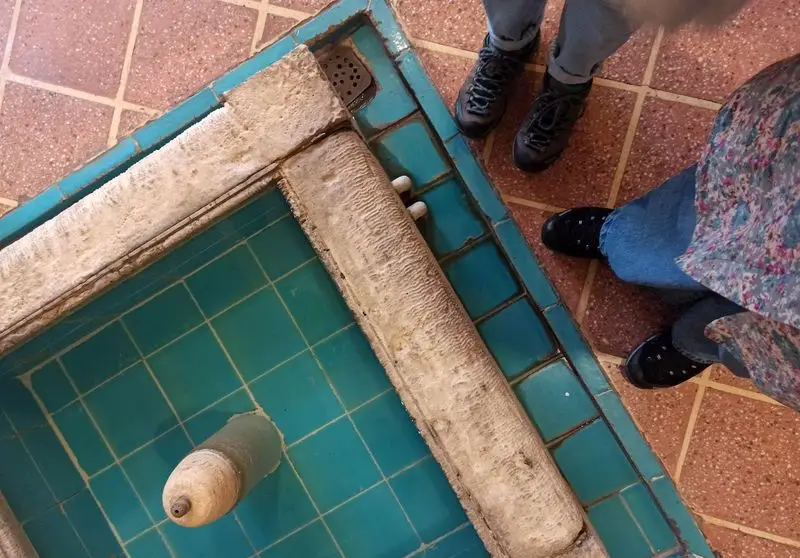 تصویر از حوضچه فیروزه‌ای و کف‌پوش کاشی‌کاری شده در رستوران ایرانی آذری، نشان‌دهنده فضای سنتی و حضور مهمانان.