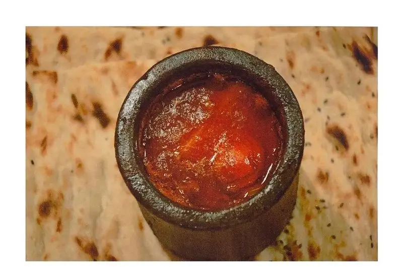 غذای محلی و خوش‌رنگ ایرانی آذری در ظرف سنتی سفالی روی نان مسطح. طعم بی‌نظیر در رستوران اصیل ایرانی آذری.