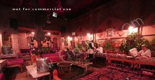 فضای سنتی و دلنشین رستوران ایرانی آذری با دکوراسیون زیبا، فرش‌های نفیس، تخت‌های چوبی و مشتریان در حال صرف غذا.