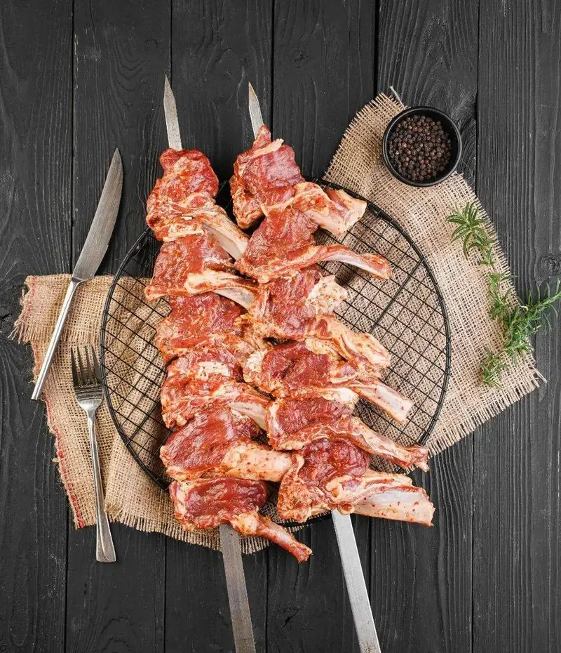 شیشلیک و دنده کباب تازه و مرینیت شده رستوران ساطور، آماده طبخ روی منقل، با ادویه و سبزیجات معطر برای یک تجربه غذایی لذیذ.