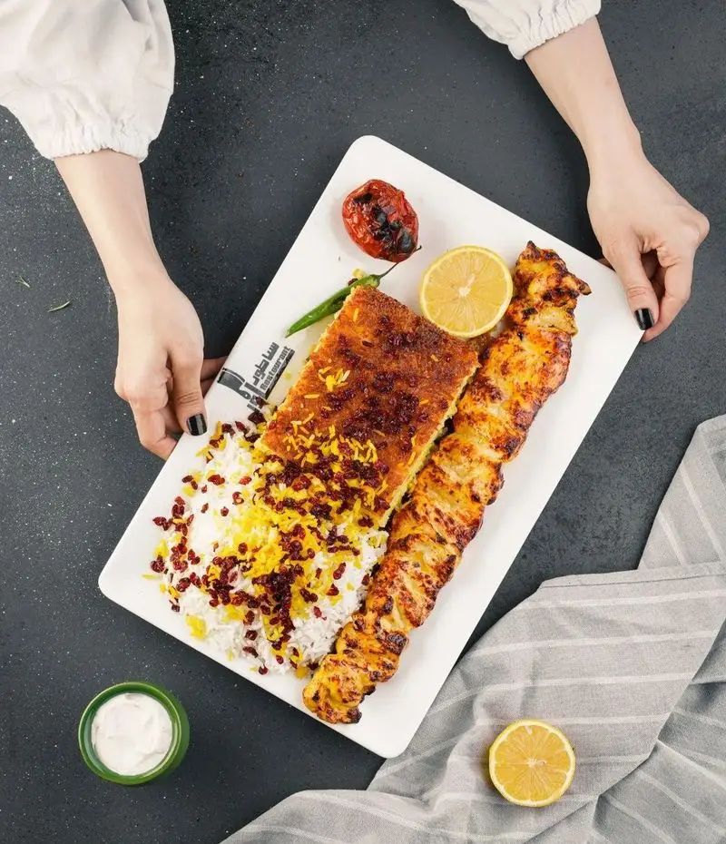 رستوران ساطور: چلو جوجه کباب لذیذ و ته چین زعفرانی با برنج ایرانی، زرشک و گوجه، تجربه‌ای دلنشین از غذای اصیل ایرانی.