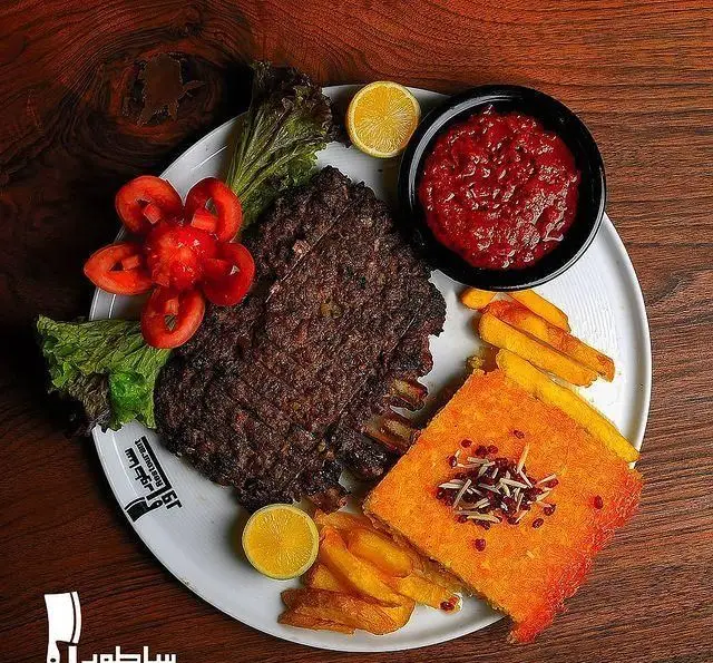 غذای خوشمزه رستوران ساطور: دنده کباب با ته چین زعفرانی، سیب زمینی سرخ کرده و سس قرمز. بهترین کباب در ایران.