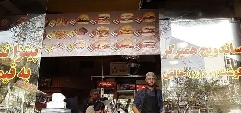 نمای فست فود پیتزایی بوراک، شامل منوی رنگارنگ انواع همبرگر، ساندویچ و غذاهای تازه با قیمت‌های مشخص و کارکنان آماده خدمت‌رسانی.