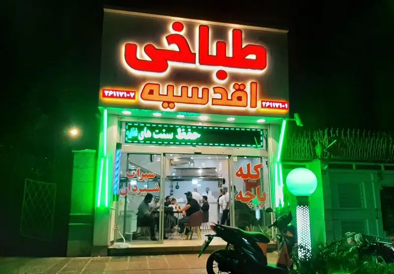 طباخی اقدسیه با تابلوی نئون قرمز روشن، ارائه دهنده کله پاچه و سیراب شیردان سنتی در فضایی گرم و دلنشین. شماره تماس: ۰۲۱۷۹۱۱۷۰۷.