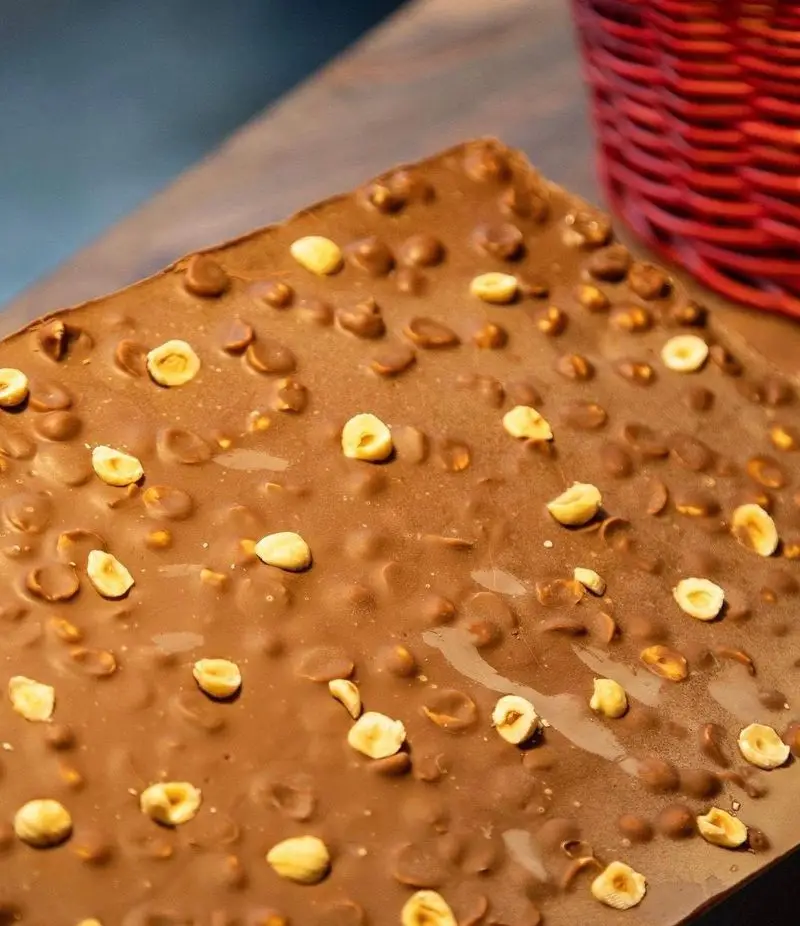 یک تخته بزرگ شکلات شیری اعلا با فندق‌های طلایی برشته و کریسپی‌های شکلاتی. دسری دلپذیر و دست‌ساز از آسایی کاسه روح.