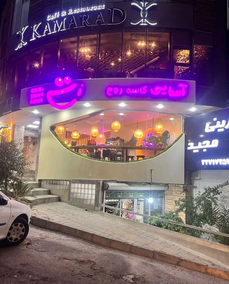 نمای بیرونی شبانه کافه و رستوران آسایی کاسه روح با تابلوی نئونی بنفش درخشان، لوگوی صورتک خندان و دکوراسیون داخلی نورانی.