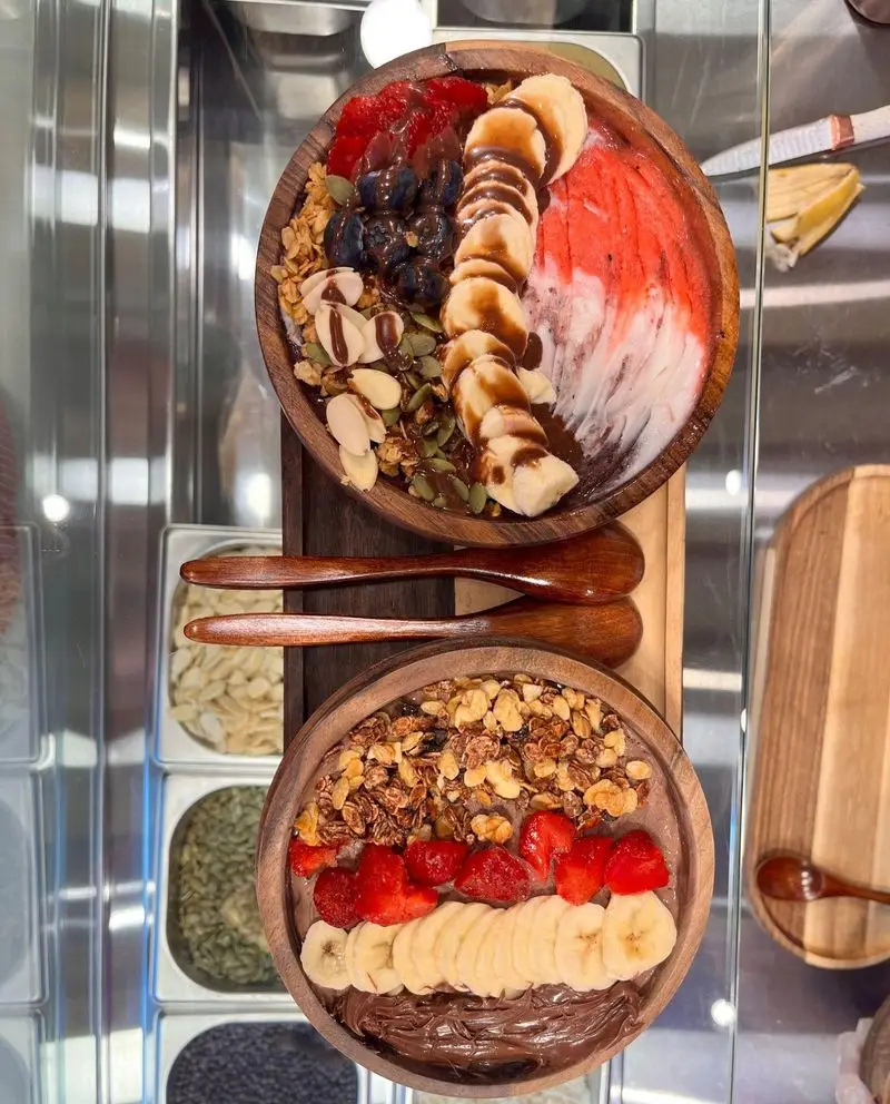 دو کاسه اسموتی میوه‌ای و سالم از آسایی کاسه روح با تزئینات گرانولا، موز، توت فرنگی، بلوبری و مغزیجات متنوع.