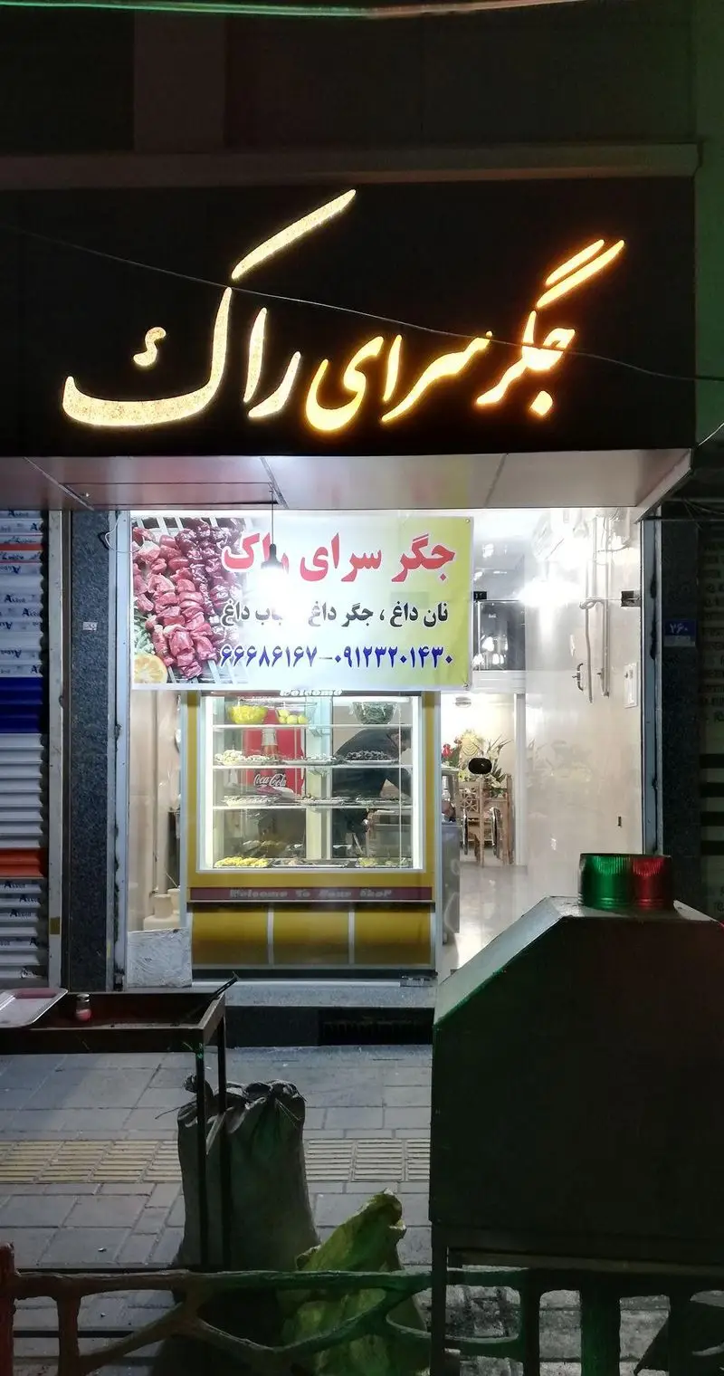 نمای شبانه رستوران جگرسرای راک با تابلوی روشن، منوی نان داغ، جگر داغ، کباب دل و قلوه و شماره تماس جهت سفارش.