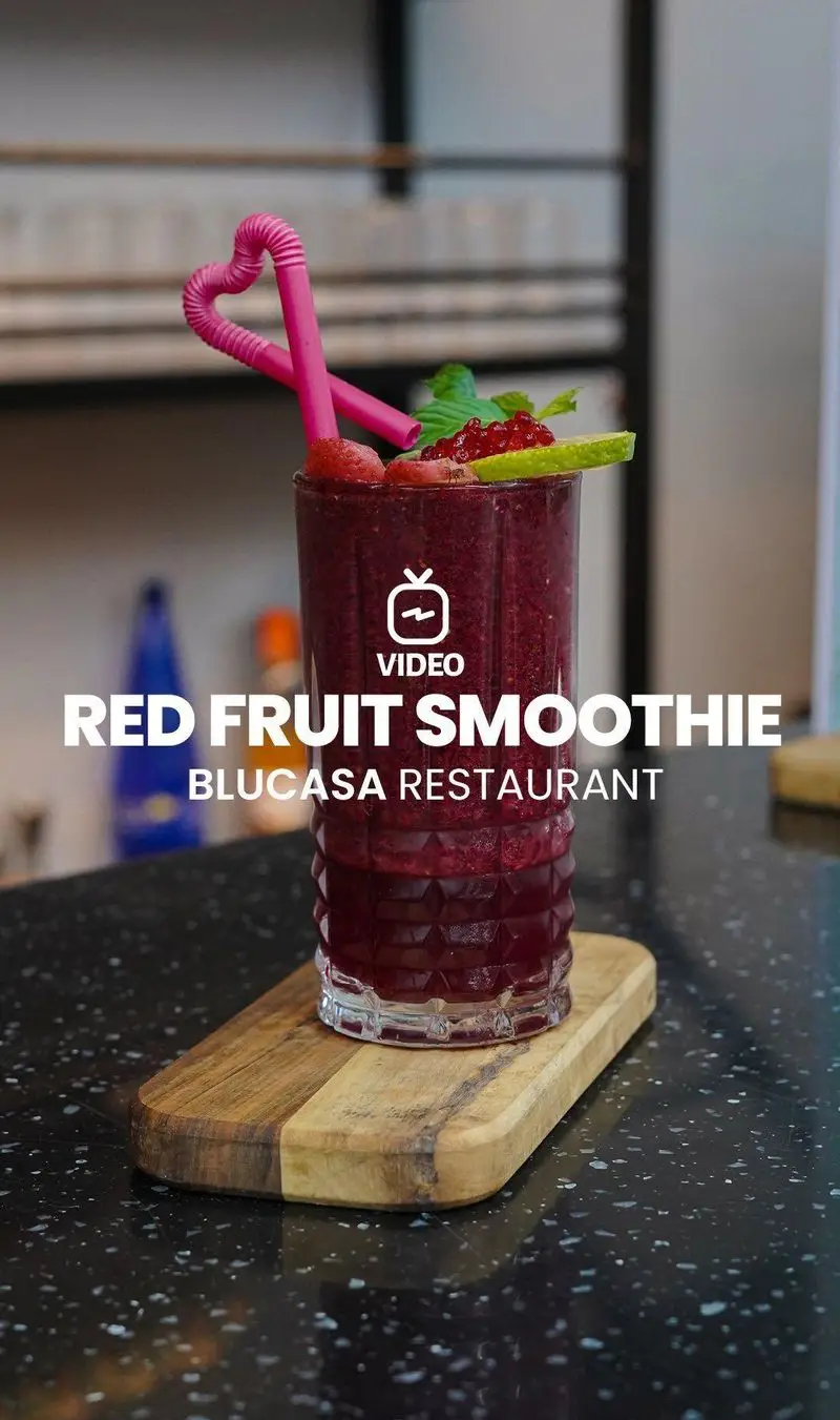 اسموتی میوه قرمز تازه و خوشمزه با نی قلبی و تزیین میوه، آماده سرو در کافه و رستوران بلوکازا برای مشتریان.